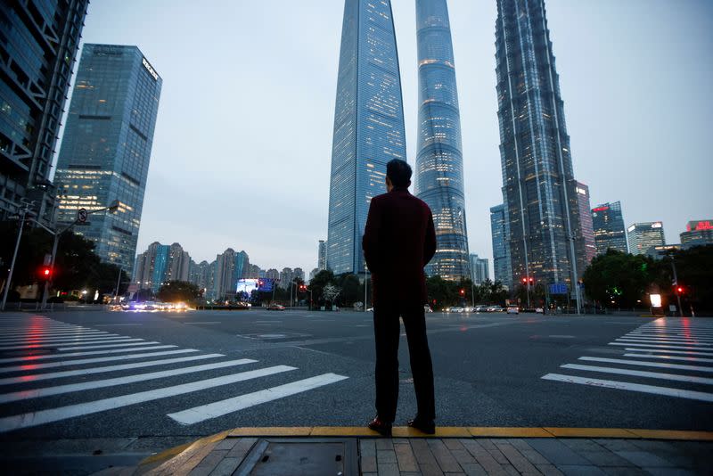 FILE PHOTO: A man stands at a crossroads in Lujiazui financial district in Pudong, Shanghai