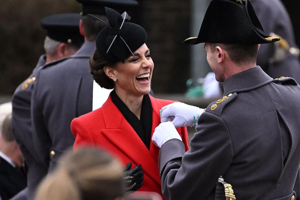 Catherine, Princess of Wales, laughs as she is pinned a leek onto her coat during a visit to the 1st Battalion Welsh Guards for St David's Day Parade