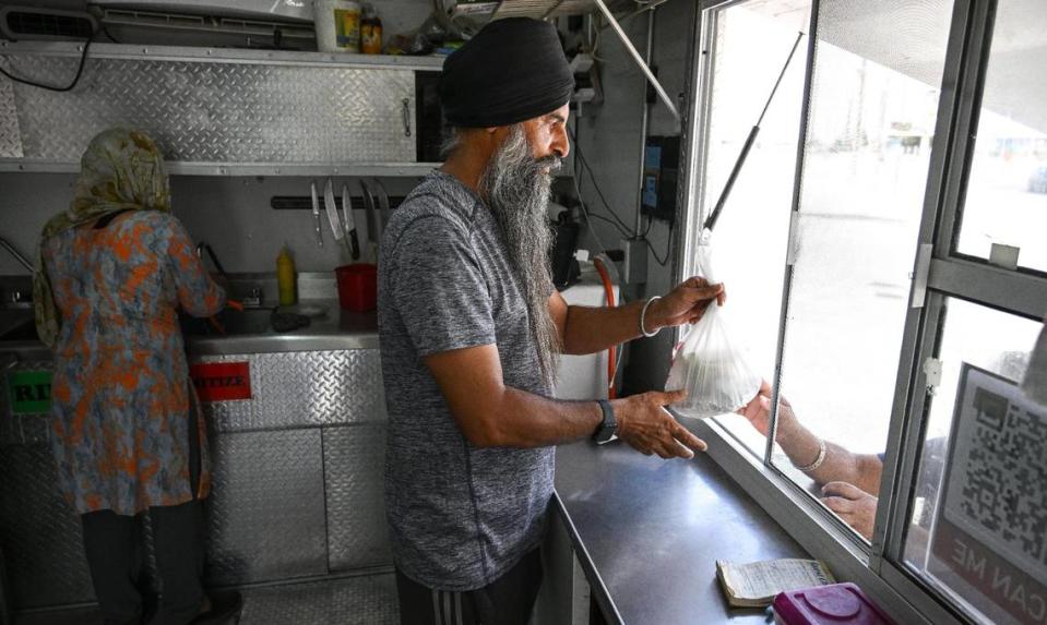Navdeep Singh hands off an oder to a customer his Punjabi Chullah & Grill food truck on Shaw Avenue near Highway 99 in Fresno on Wednesday, Aug. 16, 2023.