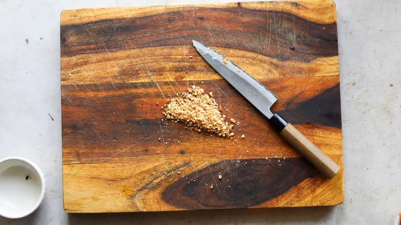 Knife chopping toasted pine nuts