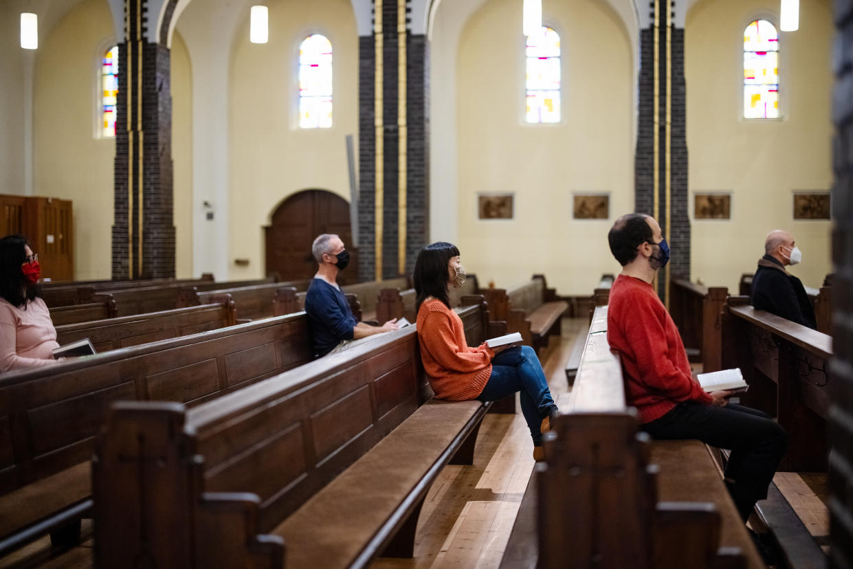 Group of people at church congregation wearing face masks. People sitting with social distance and attending religious mass at church.