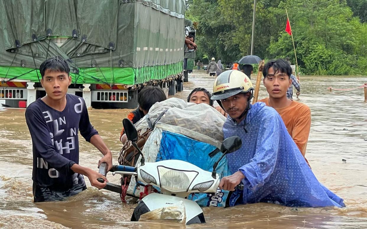 Victims of the typhoon wade through the flood water