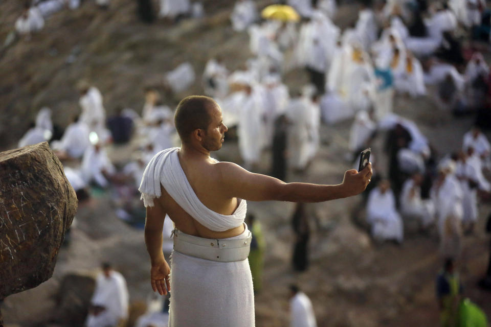 A Muslim pilgrim takes a selfie on a rocky hill known as Mountain of Mercy, on the Plain of Arafat, during the annual hajj pilgrimage, near the holy city of Mecca, Saudi Arabia, Saturday, Aug. 10, 2019. More than 2 million pilgrims were gathered to perform initial rites of the hajj, an Islamic pilgrimage that takes the faithful along a path traversed by the Prophet Muhammad some 1,400 years ago. (AP Photo/Amr Nabil)