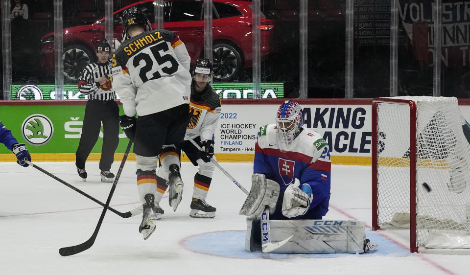 Daniel Schmolz of Germany jumps in front of Slovakia's keeper Patrik Rybar during the group A Hockey World Championship match between Slovakia and Germany in Helsinki, Finland, Saturday May 14, 2022. (AP Photo/Martin Meissner)