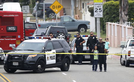 A police officer holds children evacuated from the Mission Gardens Apartments at the scene of an armed standoff with a man with a high powered rifle who is holding hostages in Chula Vista, California May 28, 2015. REUTERS/Earnie Grafton