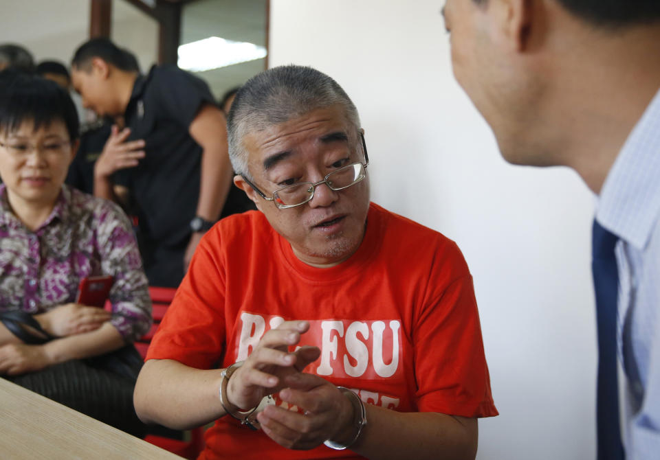 Xie Haojie, center, who was arrested in Manila in an operation coordinated with Chinese authorities, talks to Chinese officials prior to his formal turnover at a news conference in Manila, Philippines Wednesday, Jan. 16, 2019. Philippine officials have turned over to China the former government official wanted for alleged economic crime and corruption. (AP Photo/Bullit Marquez)