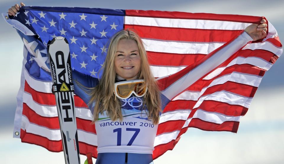 FILE -In this Feb. 20, 2010 file photo, bronze medalist Lindsey Vonn of the United States hold the Stars and Stripes during the flower ceremony for the Women's super-G at the Vancouver 2010 Olympics in Whistler, British Columbia. Vonn announced Friday, Feb. 1, 2019, that she will retire from ski racing after this month's world championships in Sweden. (AP Photo/Gero Breloer, File)