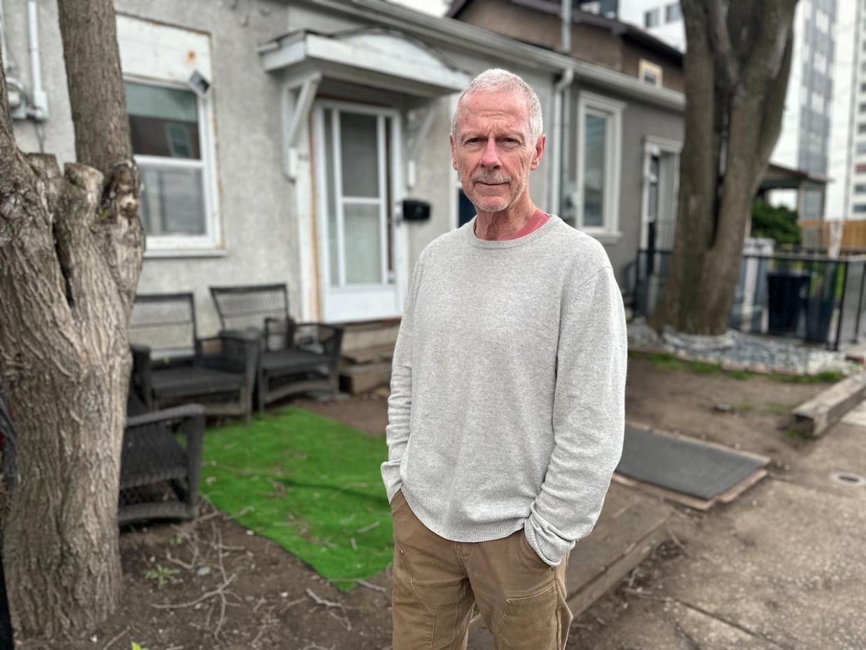 Patrick Flynn, who lives on Hess Street North in downtown Hamilton, says the couple in the row house next door, pictured behind him, are unreasonably loud and keep him up at night.  (Samantha Beattie/CBC - image credit)