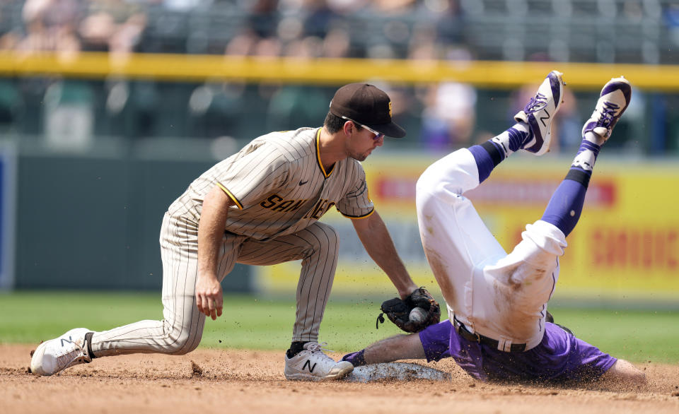 San Diego Padres second baseman Adam Frazier, left, tags out Colorado Rockies' Garrett Hampson as he tries to steal second base in the third inning of a baseball game, Wednesday, Aug. 18, 2021, in Denver. (AP Photo/David Zalubowski)