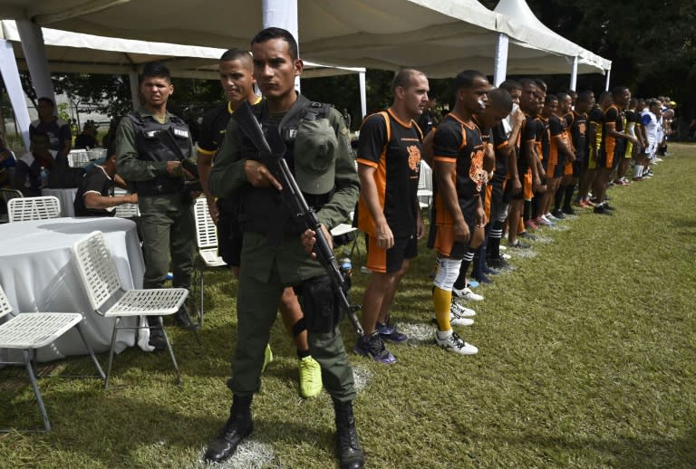 Soldiers armed with automatic rifles stand guard as inmates with the Jaguares del Rodeo rugby team stand on the sidelines during Venezuela's Penitentiary Rugby Tournament