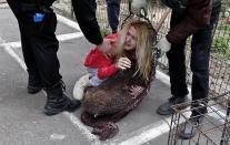 A woman embraces her dog that was taken from the streets by dog catchers who she tries to convince to release in Bucharest April 3, 2014. Her dog was later released by the dog catchers back to her. Some 60,000 strays roam Bucharest. Last year, a four-year-old boy died after he was mauled by a stray beside a Bucharest park. Street protests demanded something be done about the dogs. The authorities began enforcing the euthanasia rules, which enable city halls to put down dogs caught in public spaces if they are not adopted within two weeks. Picture taken April 3, 2014. REUTERS/Bogdan Cristel (ROMANIA - Tags: ANIMALS SOCIETY)