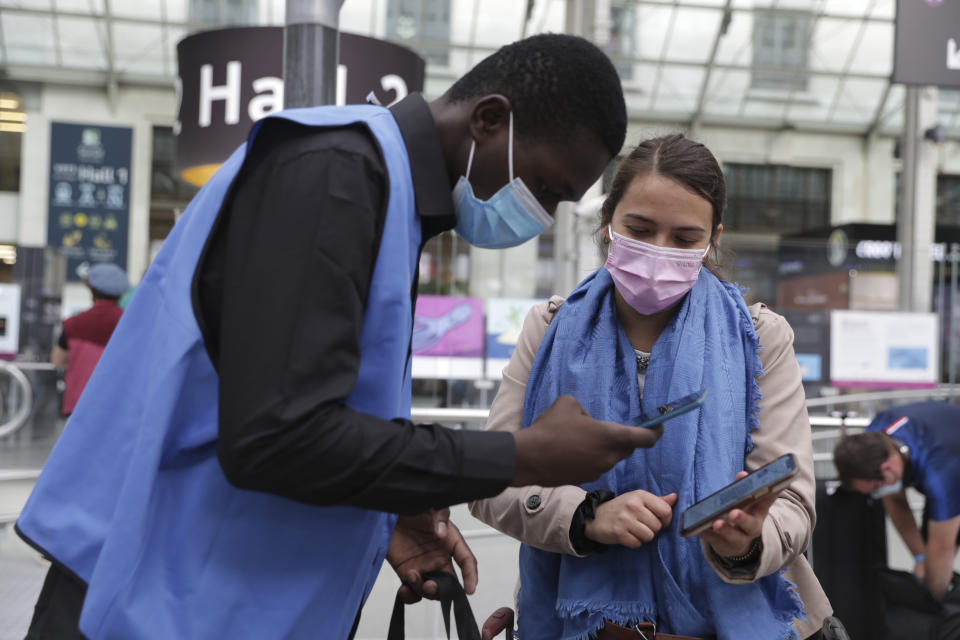 A railway employee checks the COVID-19 health pass that everyone in the country needs to enter cafes, trains and other venues, Monday Aug.9, 2021 at the Gare de Lyon train station in Paris. Starting today, the pass will be required in France to access cafes, restaurants, long-distance travel and, in some cases, hospitals. It was already in place for cultural and recreational venues, including cinemas, concert halls, sports arenas and theme parks with a capacity for more than 50 people. (AP Photo/Adrienne Surprenant)