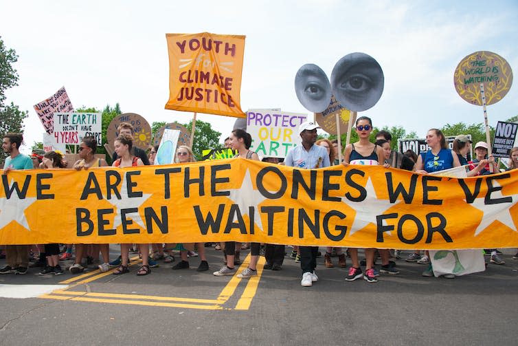 Young climate protesters carry large banner.