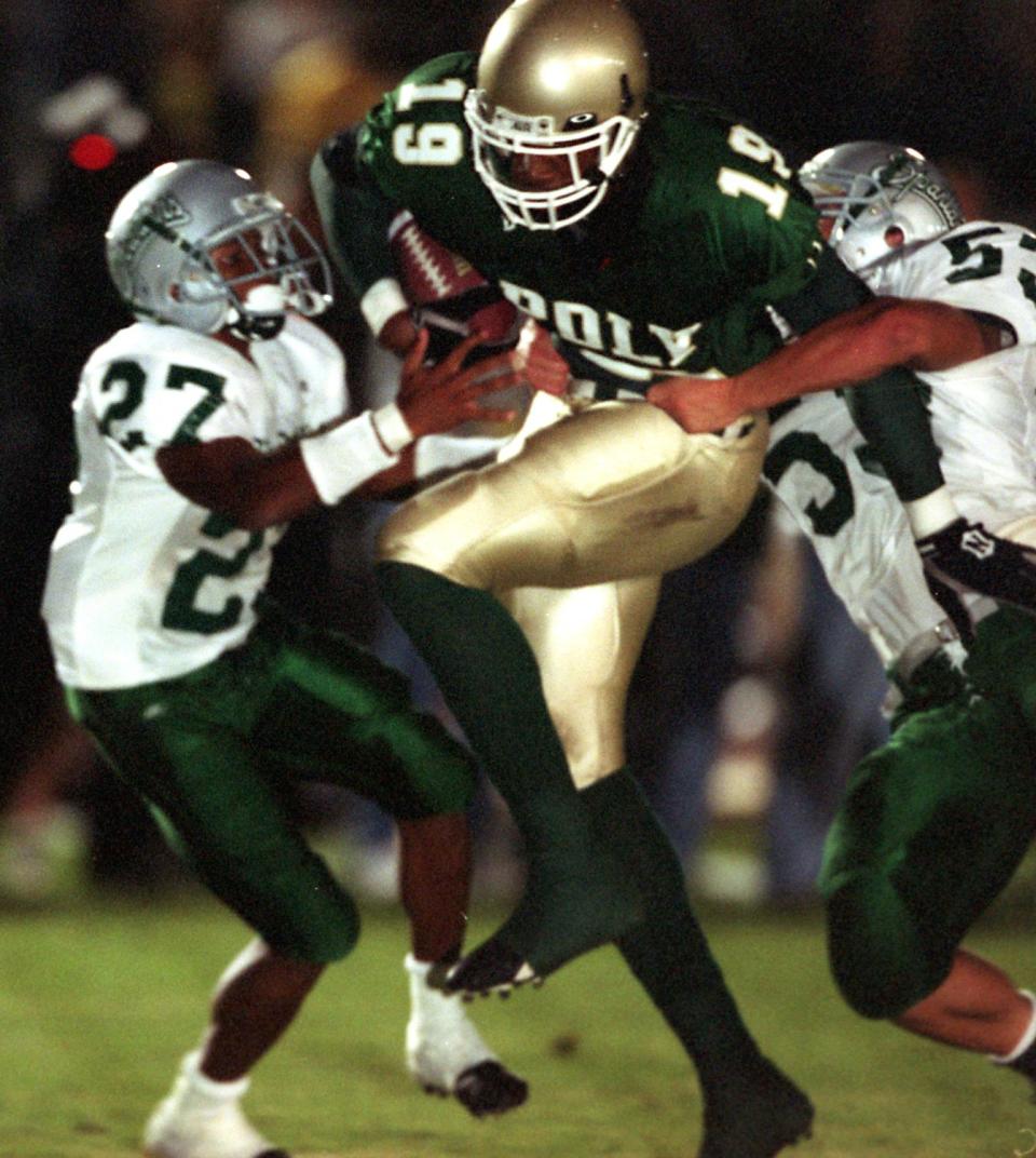 Long Beach Poly's Marcedes Lewis tries to rush past Concord De La Salle defenders Alijah Bradley and Cole Smith.