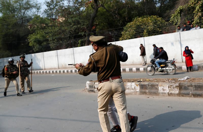 Police officer detains an unidentified man after he brandished a gun and injured a student during a protest against a new citizenship law outside the Jamia Millia Islamia university in New Delhi