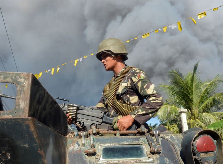 A Philippine soldier atop an armoured personnel carrier adjusts his machine gun prior to an assault on Muslim rebel positions as the stand-off enters its fifth day in Zamboanga City on September 13, 2013