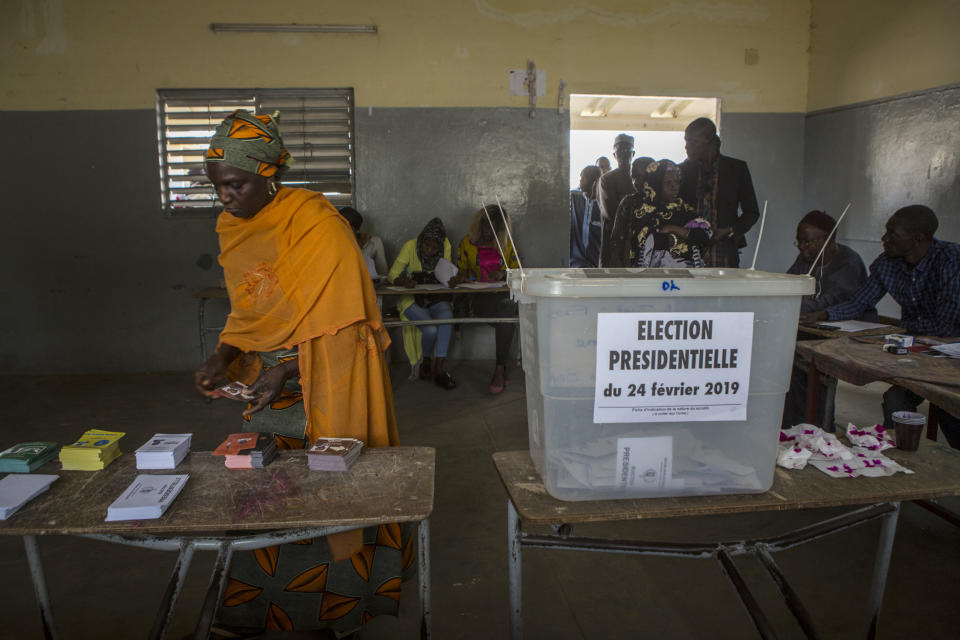 A Senegalese woman picks up voting cards before casting her ballot at a polling station in Dakar, Senegal, Sunday Feb. 24, 2019. Voters are choosing whether to give President Macky Sall a second term in office as he faces four challengers.(AP Photo/Jane Hahn)
