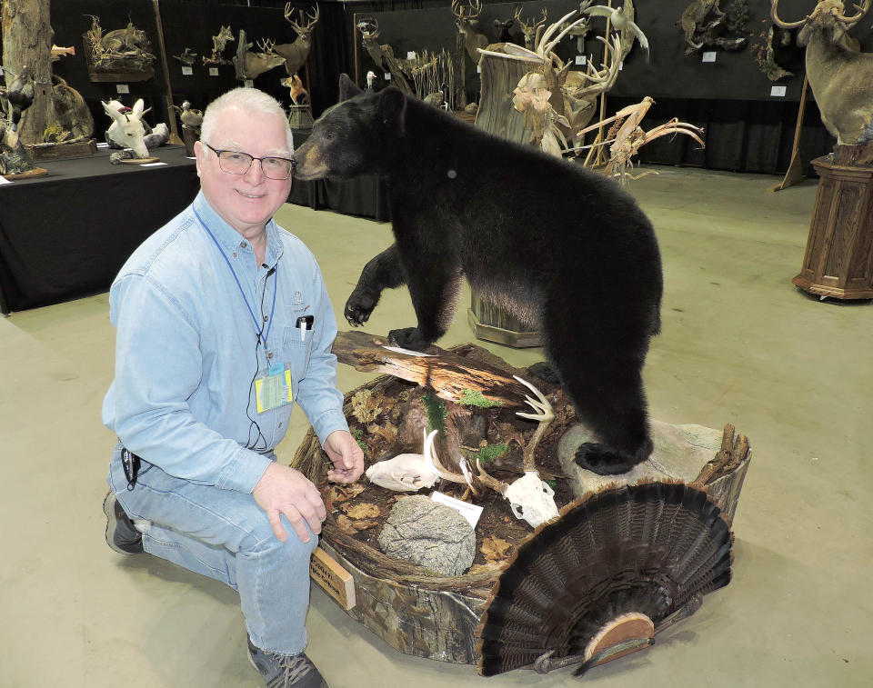 Ray Kowalski, Pennsylvania Taxidermist Association vice president from New Kensington, kneels with a taxidermy project he made for a customer who shot a bear, buck and turkey in one year. Kowalski combined the three animals into one mount.