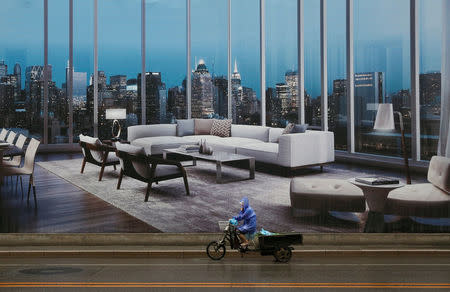 A man rides a tricycle past an advertising poster for luxury apartments in Beijing, July 19, 2016. REUTERS/Thomas Peter/File Photo