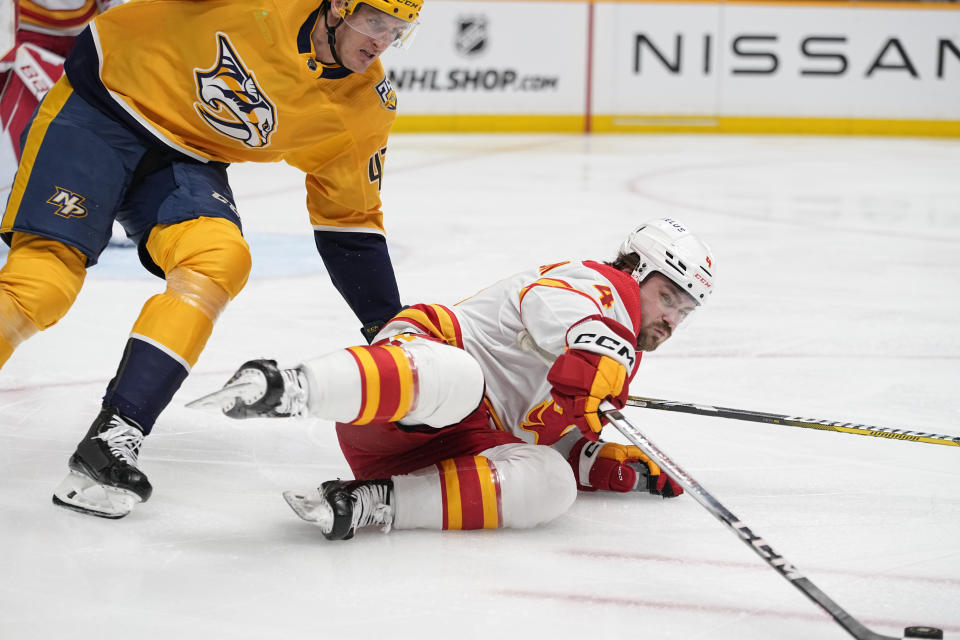 Nashville Predators right wing Michael McCarron, left, and Calgary Flames defenseman Rasmus Andersson (4) chase a loose puck during the second period of an NHL hockey game Thursday, Jan. 4, 2024, in Nashville, Tenn. (AP Photo/George Walker IV)