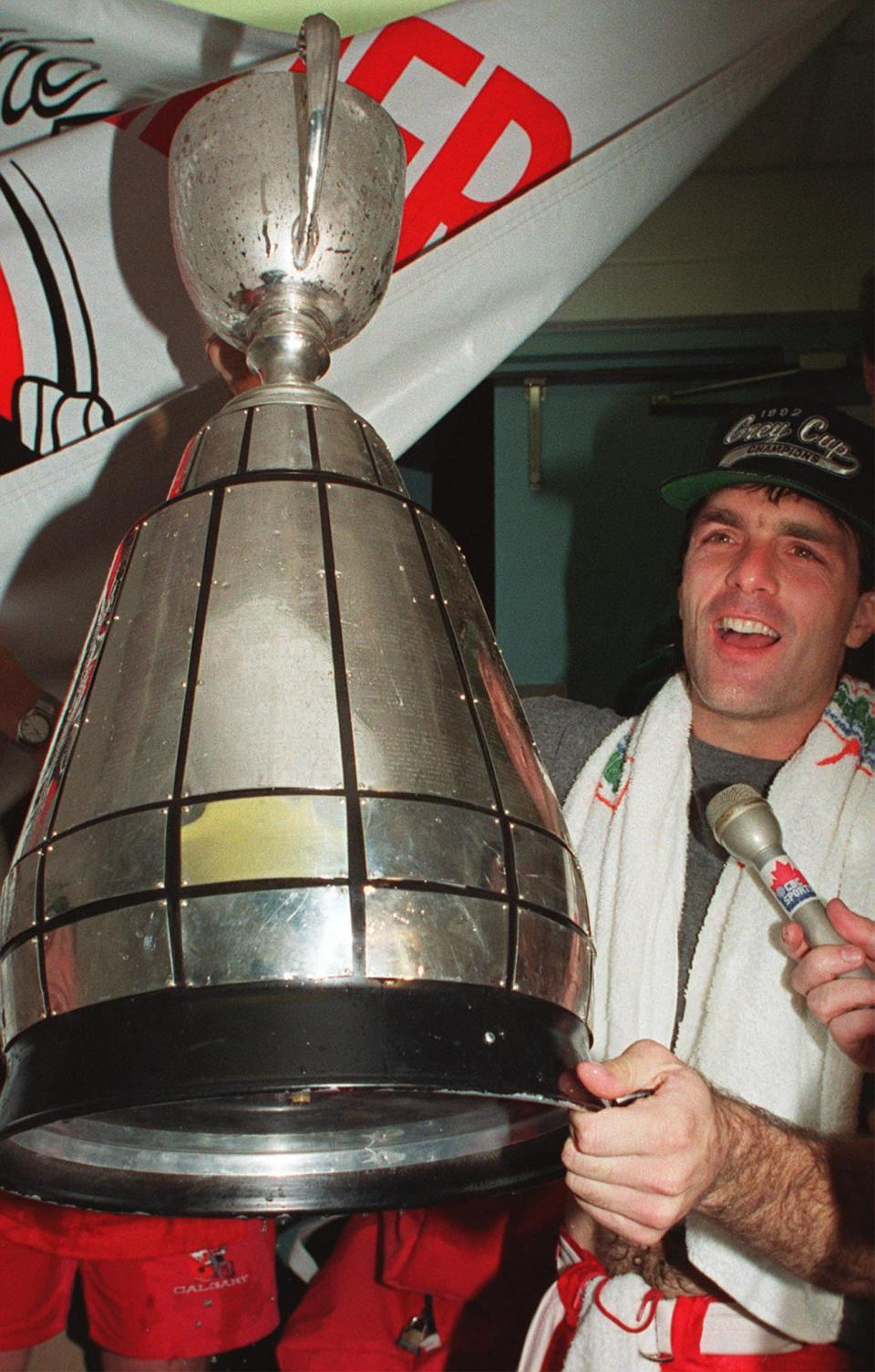 Calgary Stampeders quarterback Doug Flutie holds the Grey Cup in the team dressing room after they defeated the Winnipeg Blue Bombers at the SkyDome in Toronto in 1992. (The Canadian Press)