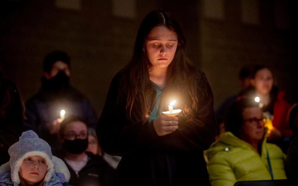 Oxford High School ninth-grader Angelina Stickney stands alongside classmates as they hold candles during a prayer vigil after the Oxford High School school shootings, - Jake May/AP