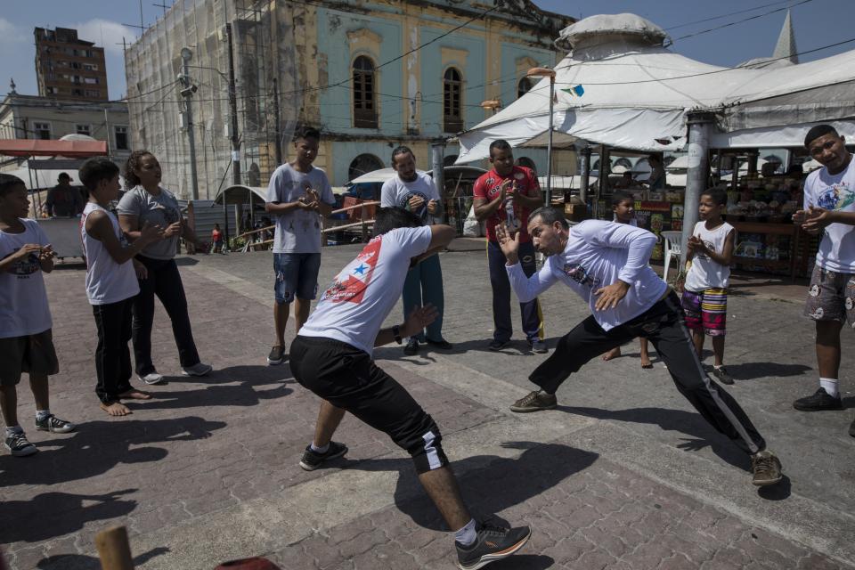 In this Sept. 1, 2019 photo, people practice capoeira at the Ver-o-Peso riverside market in Belém, Brazil. Capoeira is an Afro-Brazilian martial art that combines elements of dance, acrobatics and music. It was developed by enslaved Africans in Brazil. (AP Photo/Rodrigo Abd)