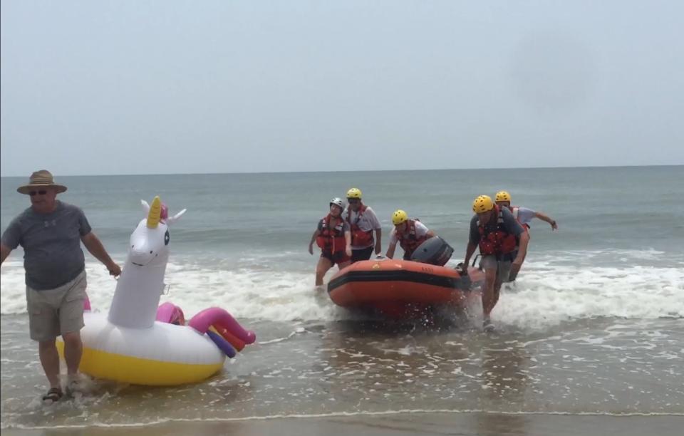 A man drags the unicorn to shore while the rescuers at Oak Island return to shore in the inflatable rescue boat.