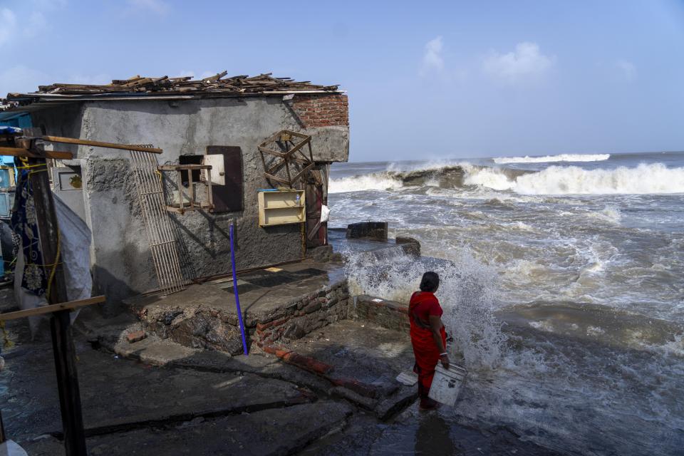 A woman stands next to her house as high tide waves hit the Arabian Sea coast in Mumbai, India, Tuesday, June 13, 2023. India and Pakistan braced for the first severe cyclone this year expected to hit their coastal regions later this week, as authorities on Monday halted fishing activities, deployed rescue personnel and announced evacuation plans for those at risk. From the Arabian Sea, Cyclone Biparjoy is aiming at Pakistan's southern Sindh province and the coastline of the western Indian state of Gujarat. (AP Photo/Rafiq Maqbool)