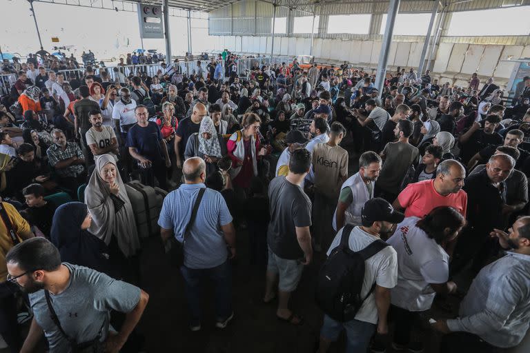 La gente espera en el cruce fronterizo entre la Franja de Gaza y Egipto en Rafah