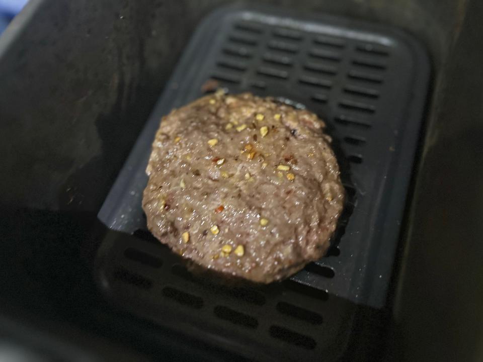 cooked burger patty in an air fryer basket