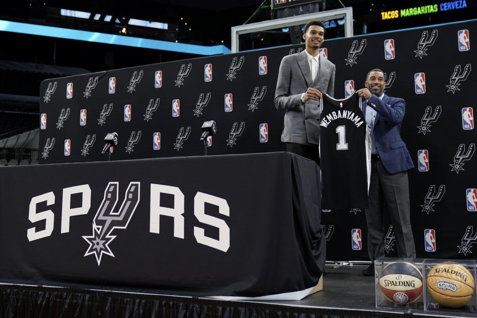 San Antonio Spurs NBA basketball first round draft pick Victor Wembanyama holds his jersey as he stands with Spurs general manager Brian Wright, right, during a news conference in San Antonio, Saturday, June 24, 2023. (AP Photo/Eric Gay)