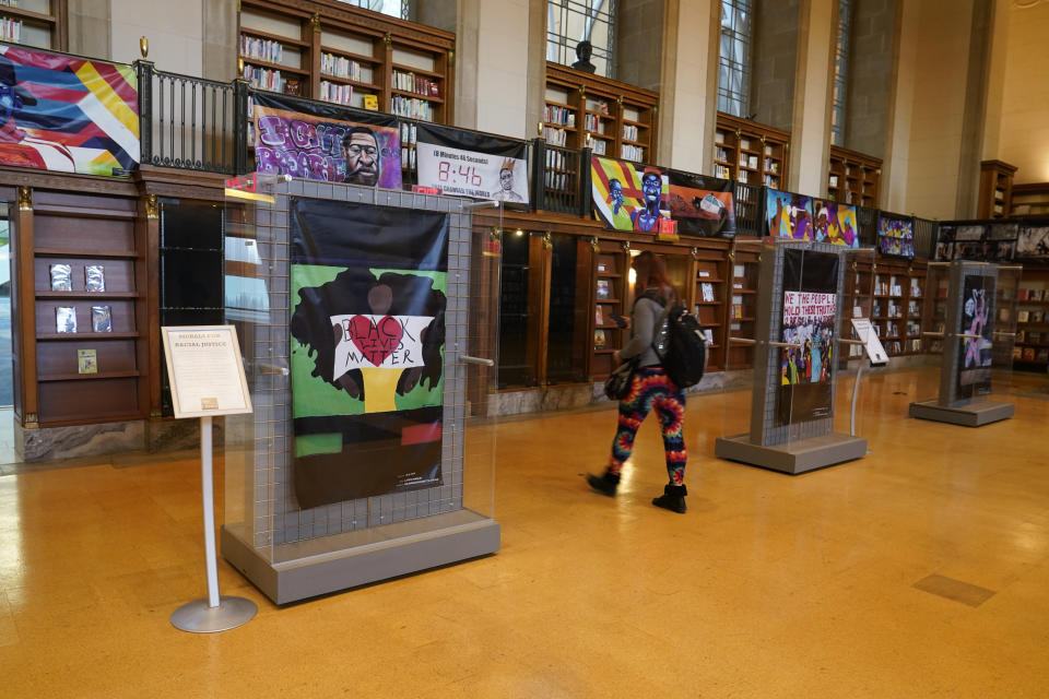 Vinyl banners representing the 24 murals that were painted in the downtown area of Indianapolis are displayed at the Central Library, Thursday, Dec. 10, 2020. During protests after George Floyd’s death, the streets of countless major cities became temporary galleries of artwork conveying collective pain and anger. But as these ephemeral artworks began to come down or be wiped from walls, patchworks of artists and activists rushed to preserve them. (AP Photo/Darron Cummings)