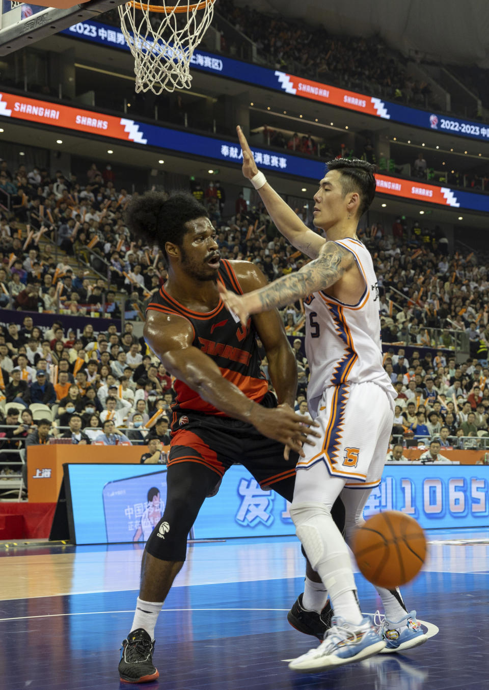 In this photo released by China's Xinhua News Agency, Devin Williams, left, of the Jiangsu Dragons passes the ball during a playoff basketball game between the Shanghai Sharks and the Jiangsu Dragons in Shanghai, Friday, April 14, 2023. The Chinese Basketball Association has ordered an investigation into a championship round game that ended with a last-minute, come-from-behind win following an series of turnovers. (Wang Xiang/Xinhua via AP)