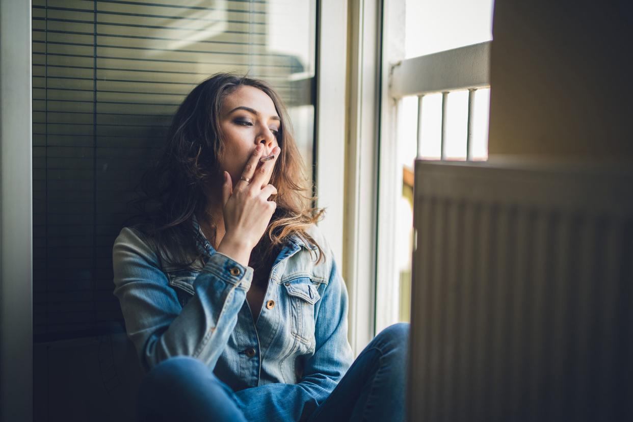 woman sitting next to the open door and smoking a cigarette