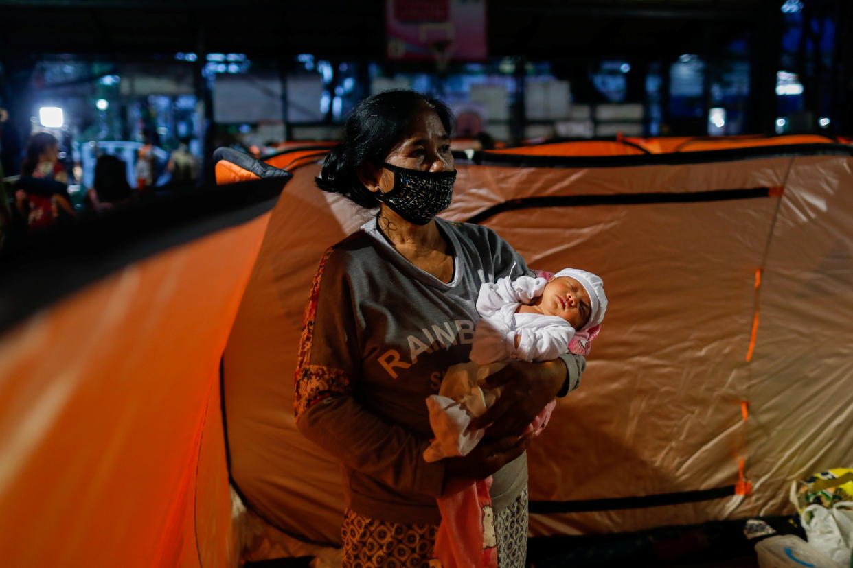 FILE PHOTO: A woman wearing a mask for protection against the coronavirus disease (COVID-19) carries a baby inside a modular tent at an evacuation center, where residents from low-lying areas took shelter following Typhoon Goni, in Quezon City, Metro Manila, Philippines, November 2, 2020. REUTERS/Eloisa Lopez