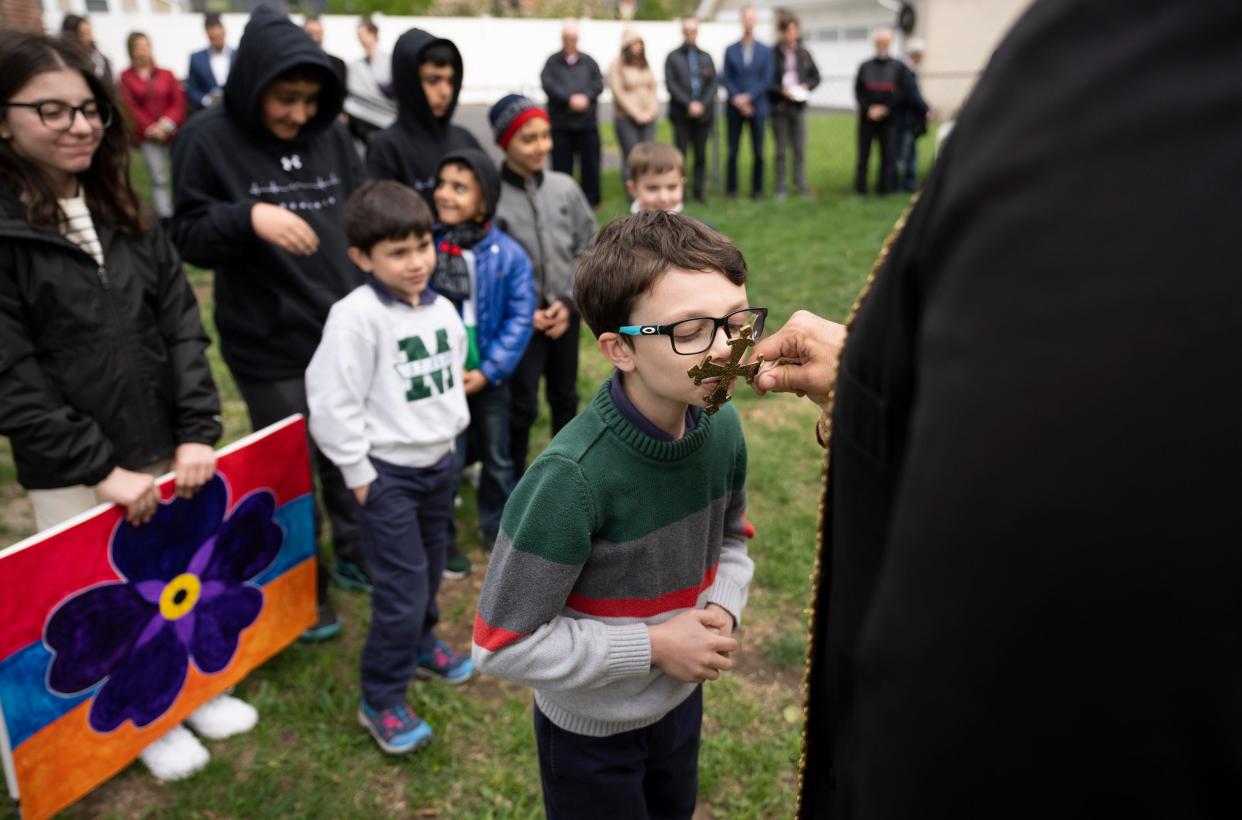 Jacob Aram Kahaian kisses a cross held by the Rev. Hratch Sargsyan during a prayer ceremony commemorating the Armenian genocide at St. James Episcopal Church in Clintonville, which shares space with the Armenian Apostolic Orthodox Church.