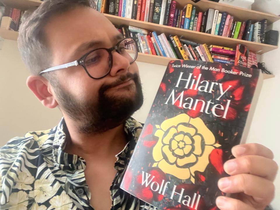 Image of Tufayel Ahmed holding up a copy of "Wolf Hall" by Hilary Mantel.