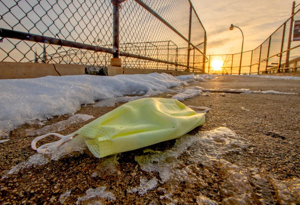 A discarded face mask lies on the pedestrian bridge over West McKinley Avenue to West Winnebago Street in Milwaukee on Tuesday, Feb. 1, 2022.