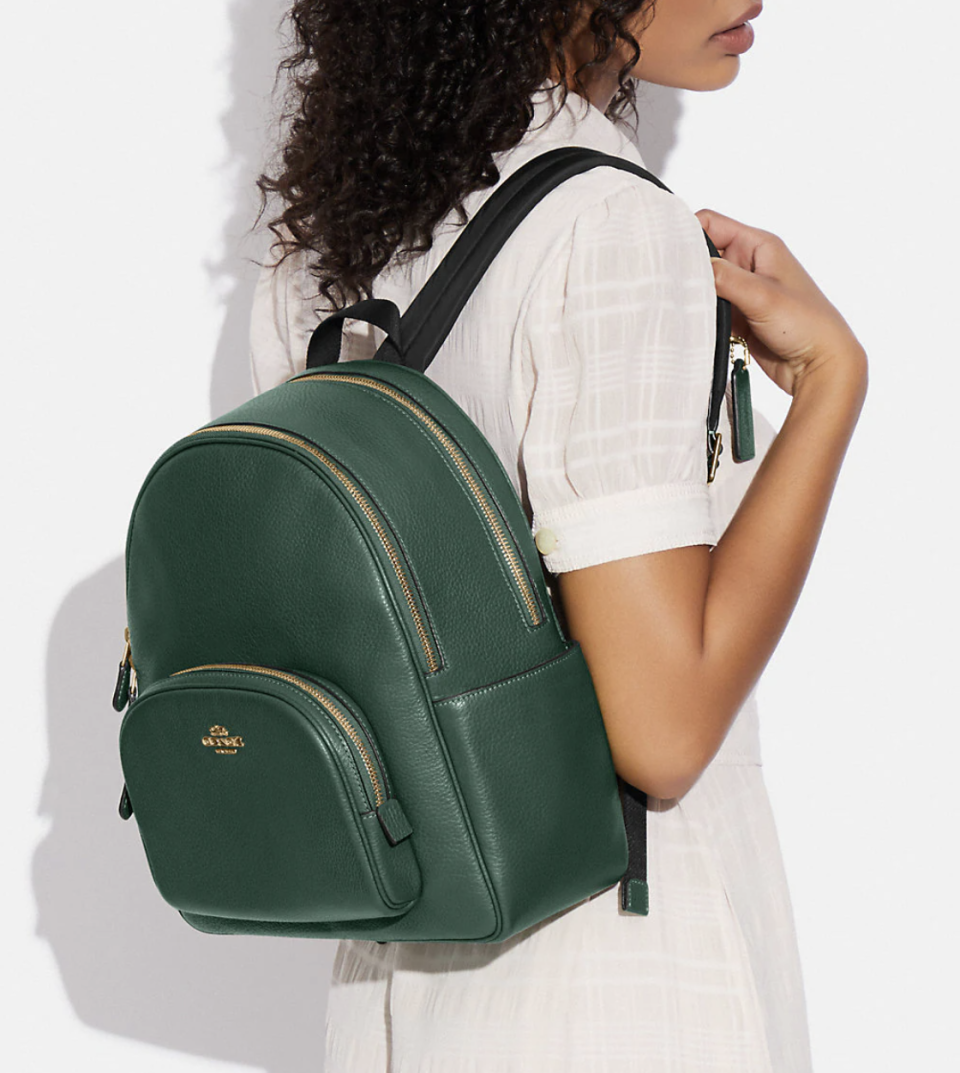 woman wearing green leather backpack, Court Backpack in everglade (photo via Coach Outlet)