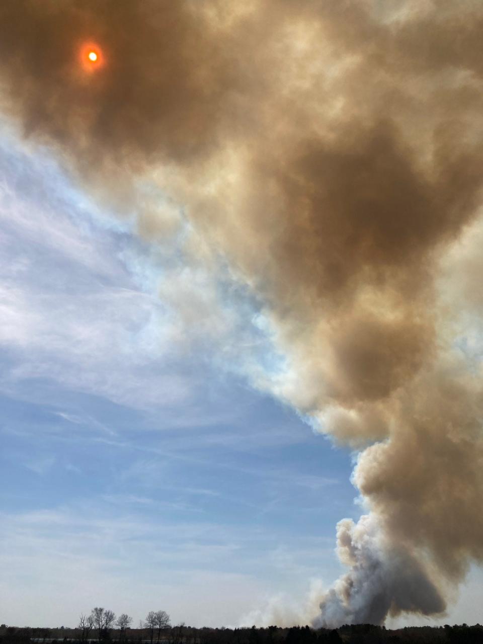 A plume of smoke rises from the April 14 Exeter wildfire. Conservationists disagree over whether the thinning of trees at Queen's River Preserve contributed to the blaze or prevented it from being worse.