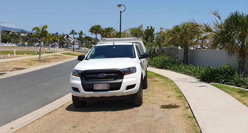 A ute is seen parked on a nature strip next to a footpath in Cannonvale in the Whitsundays.