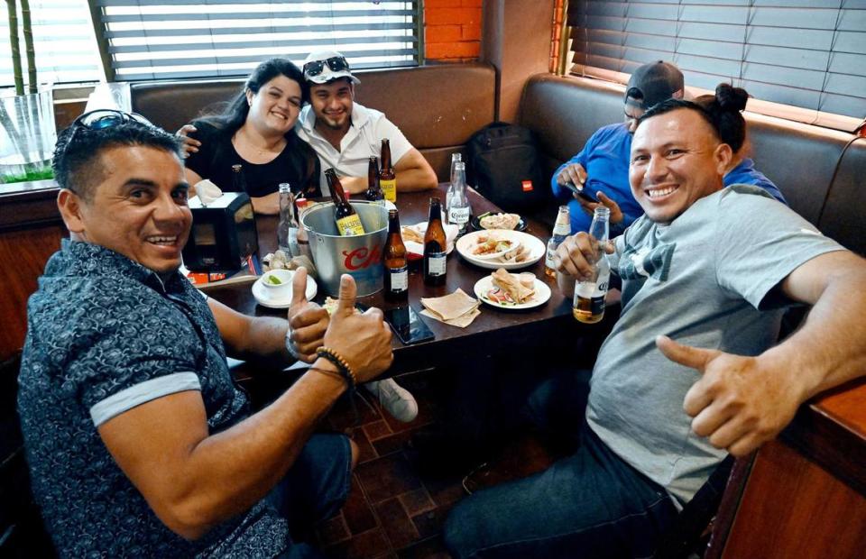 Jesus Molinares, left, and Jedlis Joel Vidaurre, right, give a thumbs up as they eat and drink with friends at El Godinazo Fresno Centro Botanero, located on Belmont in central Fresno Friday, June 23, 2023. ERIC PAUL ZAMORA/ezamora@fresnobee.com