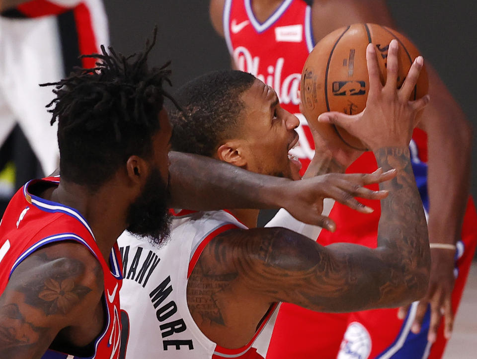 Portland Trail Blazers' Damian Lillard draws a foul from Philadelphia 76ers' Norvel Pelle, left, during the third quarter of an NBA basketball game Sunday, Aug. 9, 2020, in Lake Buena Vista, Fla. (Kevin C. Cox/Pool Photo via AP)