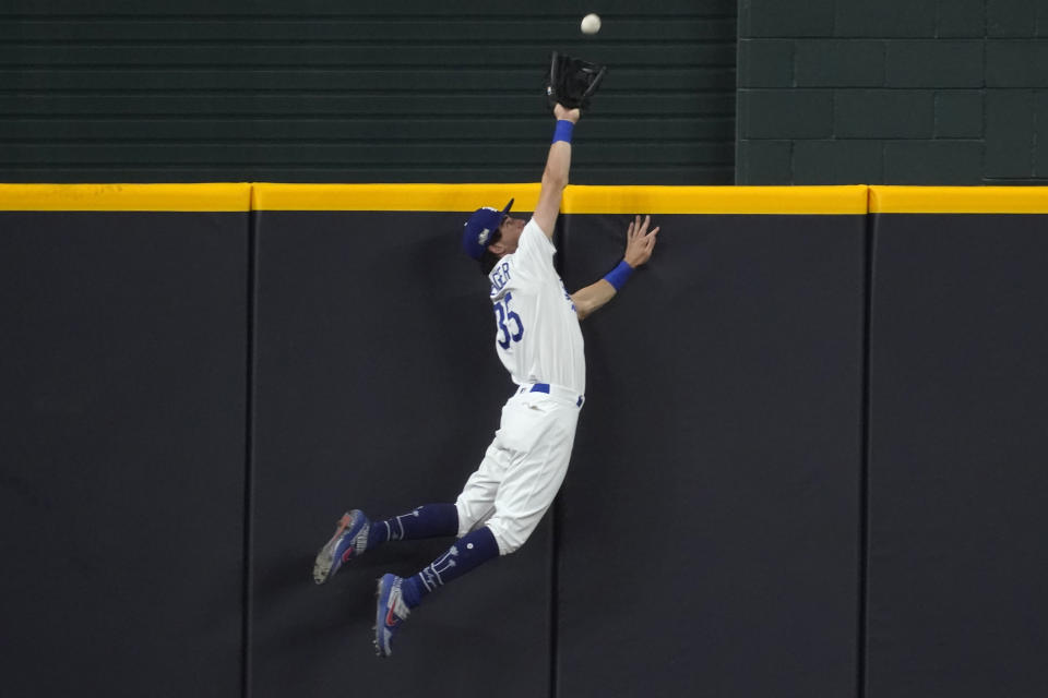 Los Angeles Dodgers' Cody Bellinger slams into the outfield wall and makes the catch as he robs San Diego Padres' Fernando Tatis Jr. of a home run on a deep drive during the seventh inning in Game 2 of a baseball National League Division Series Wednesday, Oct. 7, 2020, in Arlington, Texas. (AP Photo/Tony Gutierrez)