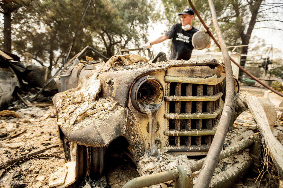 Mark Hanson goes through the remains of a 1951 Willys-Overland Jeepster following the LNU Lightning Complex fires in Vacaville, Calif., on Friday, Aug. 21, 2020. The blaze destroyed his family home as well as the Jeepster which his father purchased new and Mark rebuilt while in high school. (AP Photo/Noah Berger)