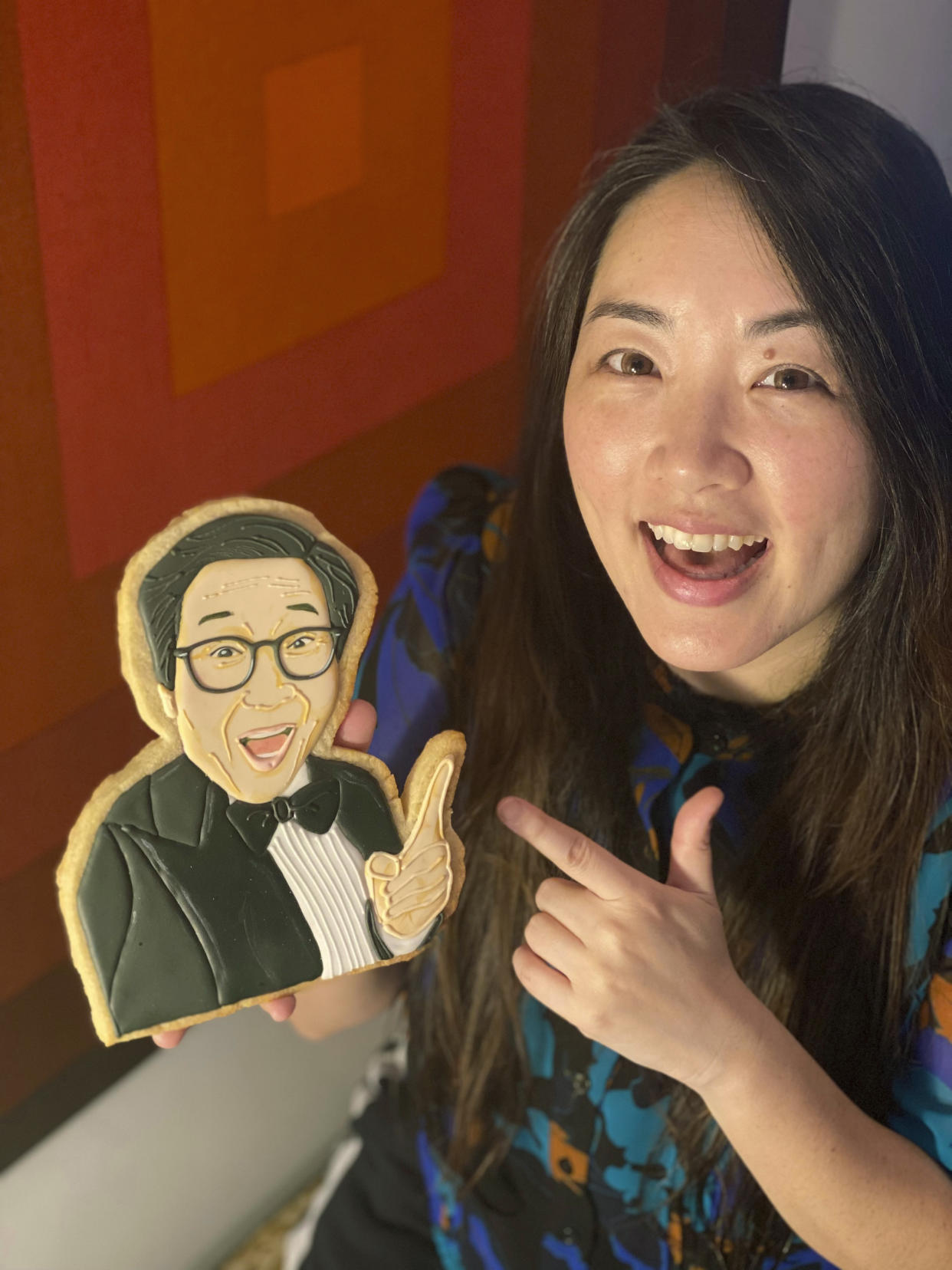 This undated photo provided by Jasmine Cho shows Cho with a cookie portrait of Ke Huy Quan's character from "Everything Everywhere All at Once" made by Cho, a "cookie activist" based in Pittsburgh. Quan's best supporting actor win and comeback story from childhood star of '80s flicks, coupled with Michelle Yeoh's historic win as the first Asian best actress winner ever had viewers of Asian descent shedding tears of happiness — and grinning. The "Everything Everywhere All at Once" co-stars bring the total number of Asians who have earned acting Oscars to just six in the awards' 95-year history. (Jasmine Cho via AP)