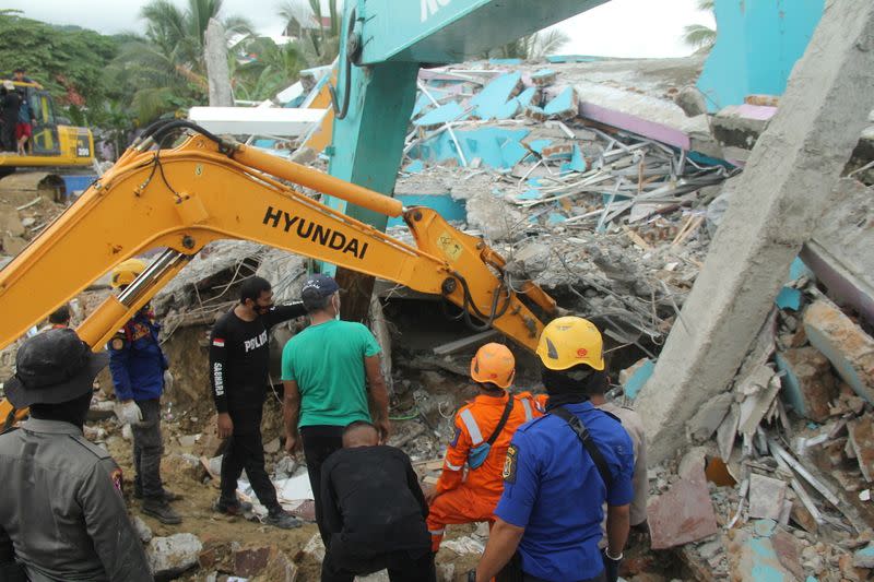 Rescuers use an excavator to dig through a damaged hospital building to search for survivors following an earthquake in Mamuju