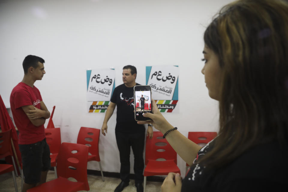 In this Thursday, Aug. 29, 2019 photo, an activist takes a photo of Ayman Odeh, the leader of the Arab Joint List parties, during a campaign meeting in Nazareth, Israel. Odeh has shaken up Israel's election campaign by offering to sit in a moderate coalition government _ a development that would upend decades of convention that has relegated Arab parties to the sidelines and could bring down Prime Minister Benjamin Netanyahu. (AP Photo/Mahmoud Illean)