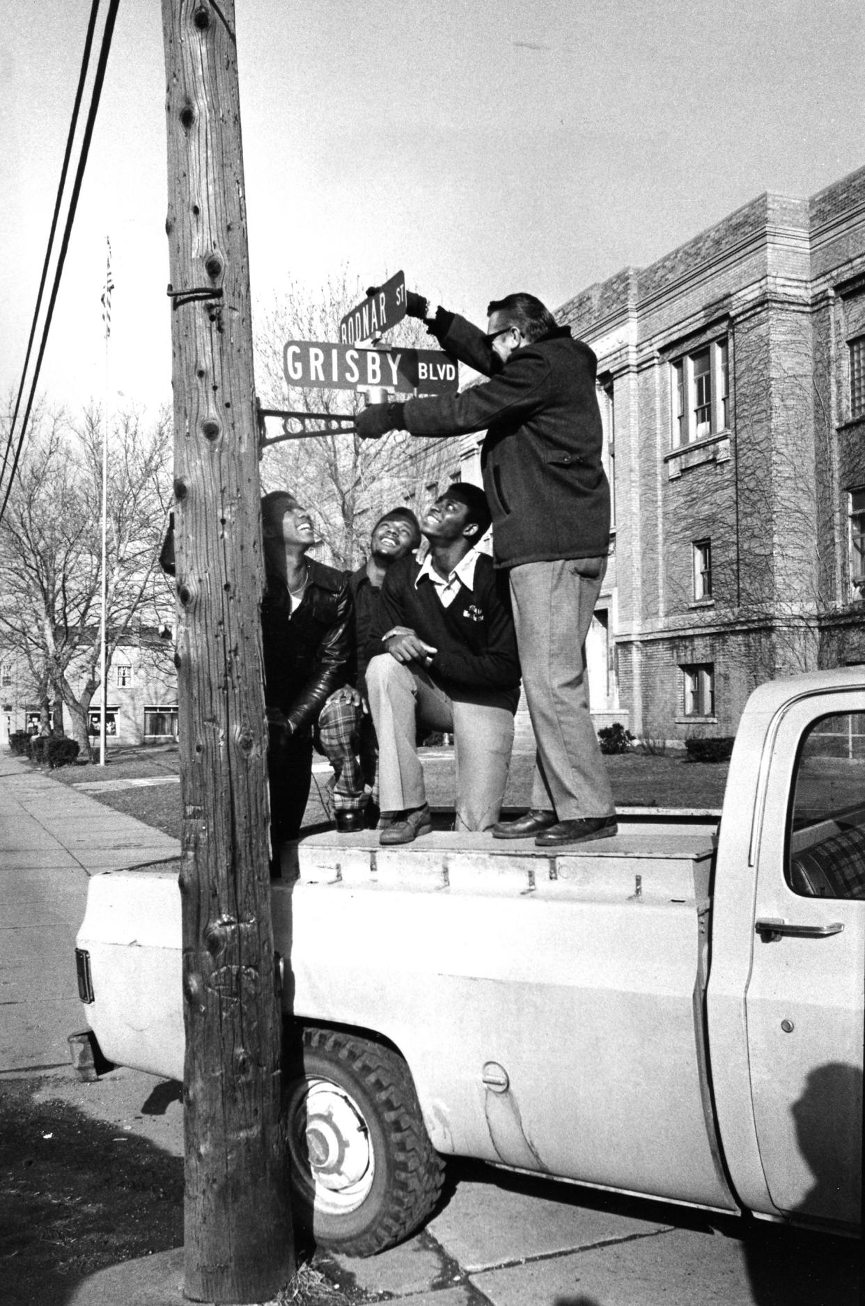 From left, Barberton High School basketball players Carter Scott, Fred Grisby and Tony Ward watch as city employee Gene Furman installs a tournament-time street sign in March 1977. Using players' surnames, Barberton temporarily renamed 12 streets to support the Magics.